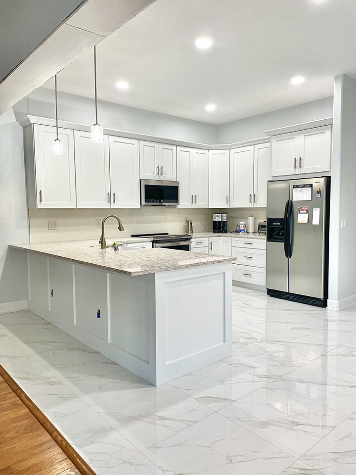 Luxury white kitchen with full custom cabinetry and pendant ceiling lights